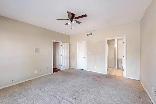 unfurnished bedroom featuring a closet, ceiling fan, light colored carpet, and ensuite bathroom