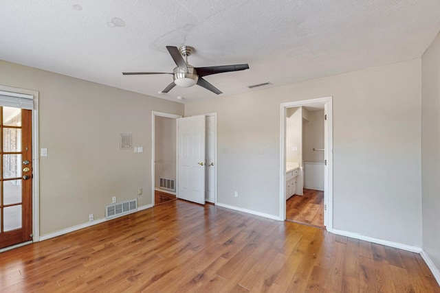 unfurnished bedroom featuring a textured ceiling, ceiling fan, light hardwood / wood-style flooring, and ensuite bathroom