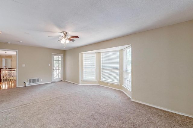 carpeted spare room featuring ceiling fan and a textured ceiling