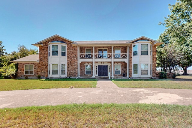 view of front facade featuring a front yard and a balcony