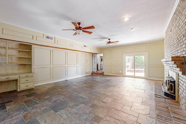 unfurnished living room with ornamental molding, a brick fireplace, and ceiling fan