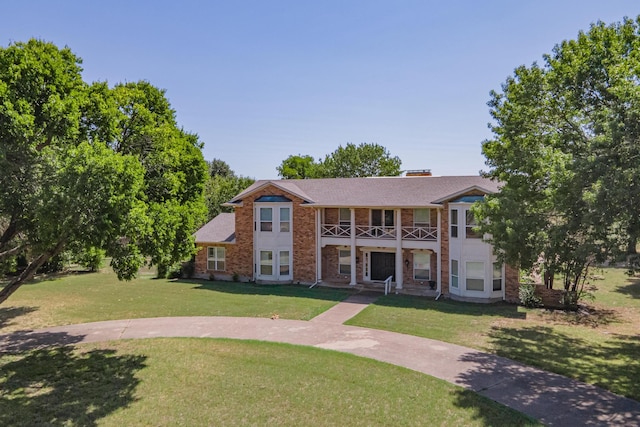 view of front of property featuring a balcony and a front yard