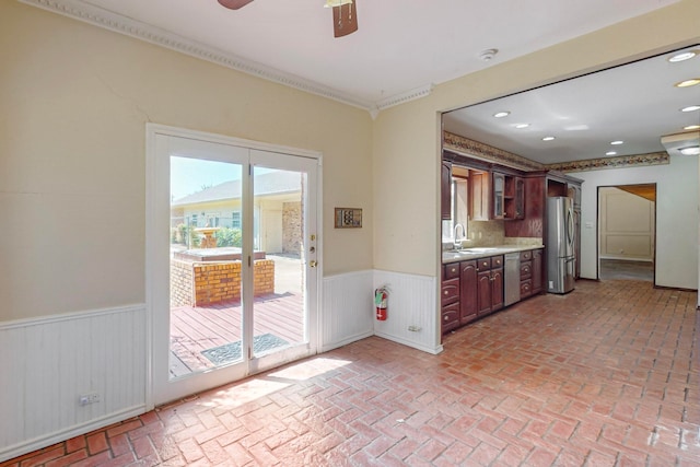 kitchen with appliances with stainless steel finishes, ornamental molding, sink, and ceiling fan