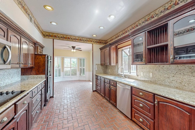 kitchen with ceiling fan, light stone counters, sink, tasteful backsplash, and stainless steel appliances