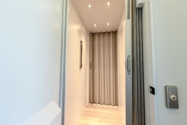 hallway with elevator and light hardwood / wood-style floors