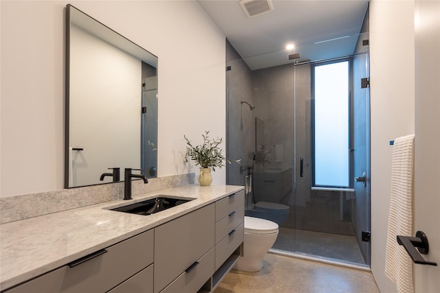 bathroom featuring a shower with shower door, toilet, and vanity