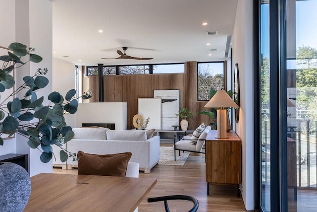 living room featuring a wall of windows, ceiling fan, and hardwood / wood-style floors