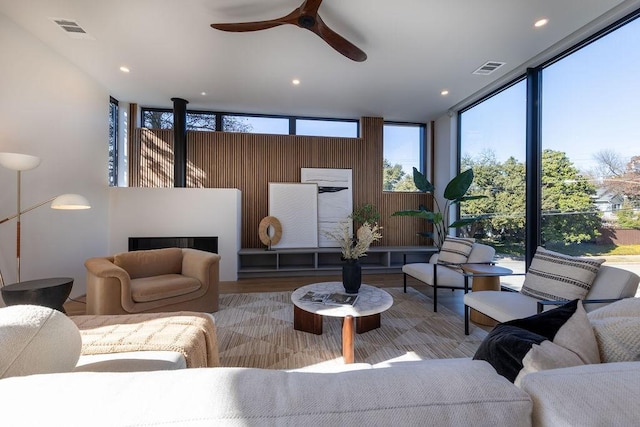 living room featuring ceiling fan, light hardwood / wood-style flooring, floor to ceiling windows, and a fireplace