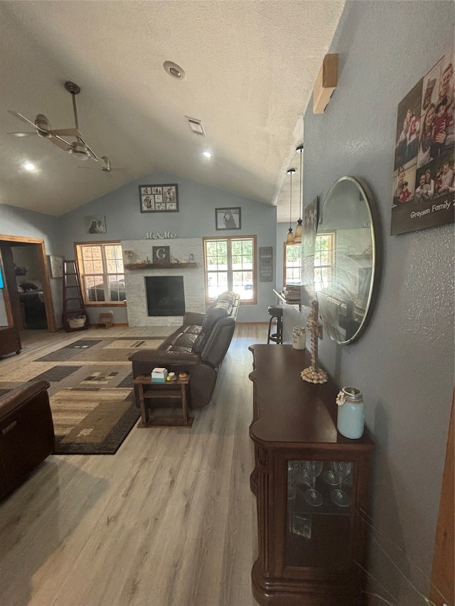 living room featuring ceiling fan, a textured ceiling, lofted ceiling, and hardwood / wood-style floors