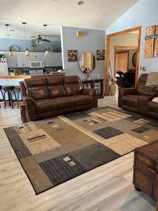 living room with light wood-type flooring, lofted ceiling, and ceiling fan