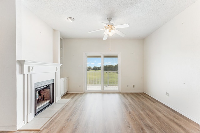 unfurnished living room featuring ceiling fan, light hardwood / wood-style floors, and a textured ceiling