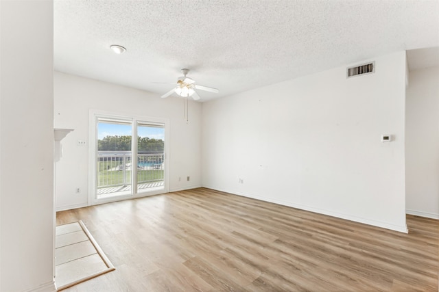 empty room with a textured ceiling, ceiling fan, and light wood-type flooring