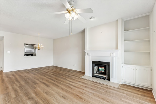 unfurnished living room with ceiling fan with notable chandelier and light wood-type flooring