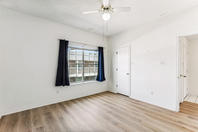 unfurnished room with ceiling fan, a textured ceiling, and light wood-type flooring