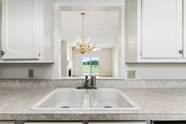 kitchen with white cabinetry, sink, a notable chandelier, and decorative light fixtures