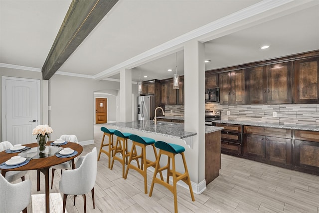 kitchen featuring hanging light fixtures, sink, an island with sink, appliances with stainless steel finishes, and light stone counters