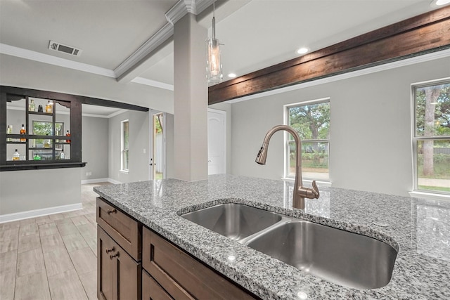 kitchen featuring light stone counters, sink, and hanging light fixtures