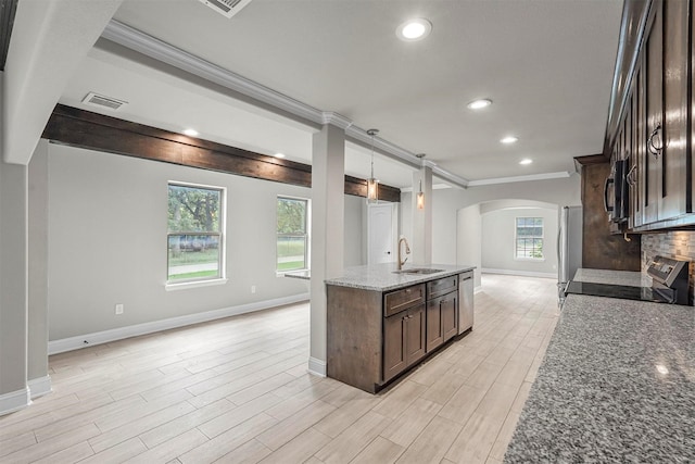 kitchen with sink, dark stone countertops, appliances with stainless steel finishes, decorative light fixtures, and dark brown cabinetry