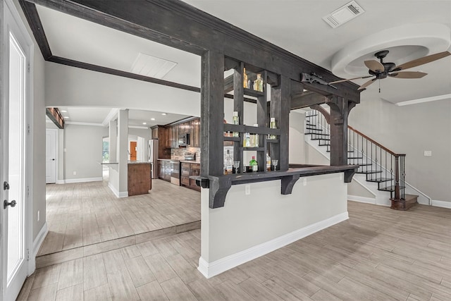 interior space with a breakfast bar, ceiling fan, ornamental molding, appliances with stainless steel finishes, and kitchen peninsula