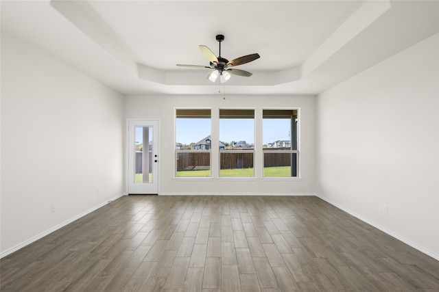 empty room featuring dark hardwood / wood-style flooring, a raised ceiling, and ceiling fan