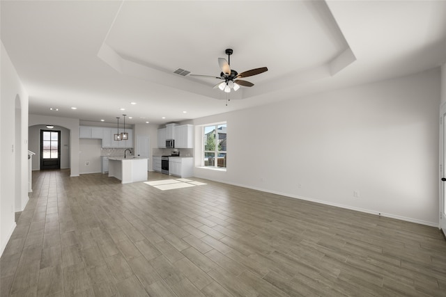 7701 Oakmeade St, Joshua, TX 76058 - unfurnished living room featuring ceiling fan, recessed lighting, healthy amount of natural light, arched walkways, and a tray ceiling