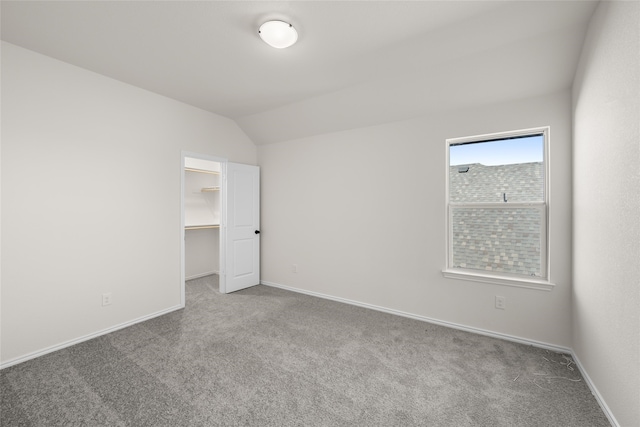 carpeted spare room with lofted ceiling