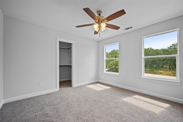 unfurnished bedroom featuring carpet floors, ceiling fan, a walk in closet, and a closet