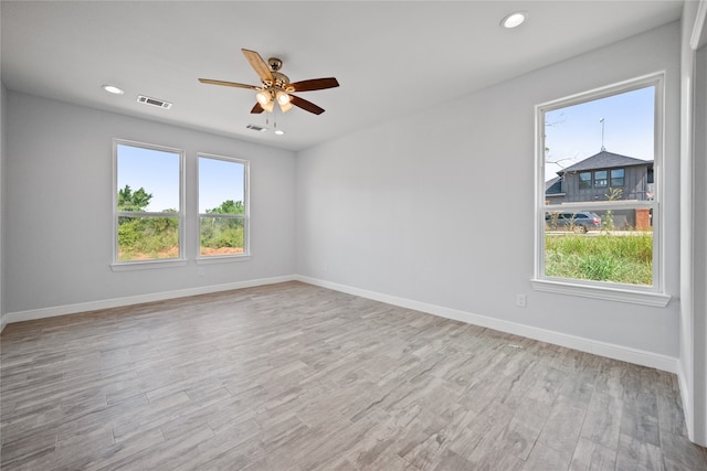 spare room featuring light hardwood / wood-style floors, ceiling fan, and a wealth of natural light