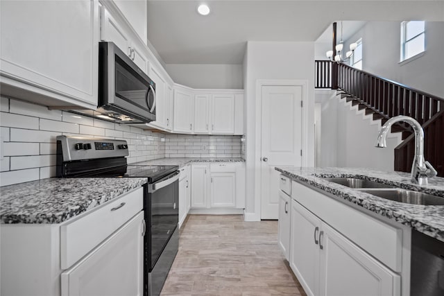 kitchen featuring light wood-type flooring, sink, white cabinetry, appliances with stainless steel finishes, and light stone countertops