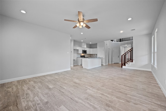 unfurnished living room featuring ceiling fan and light hardwood / wood-style floors