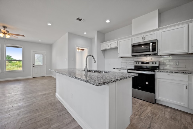 kitchen featuring sink, white cabinetry, a center island with sink, appliances with stainless steel finishes, and ceiling fan