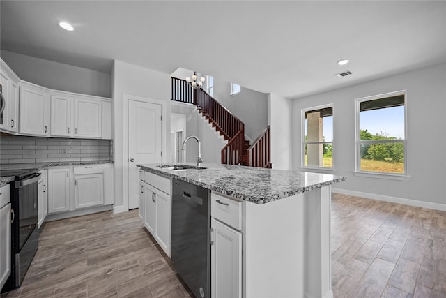 kitchen with an island with sink, sink, light hardwood / wood-style flooring, white cabinetry, and black appliances