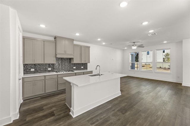 kitchen with gray cabinetry, gas stovetop, ceiling fan, a kitchen island with sink, and sink