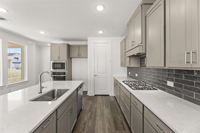 kitchen with sink, dark hardwood / wood-style floors, gray cabinets, light stone counters, and stainless steel appliances