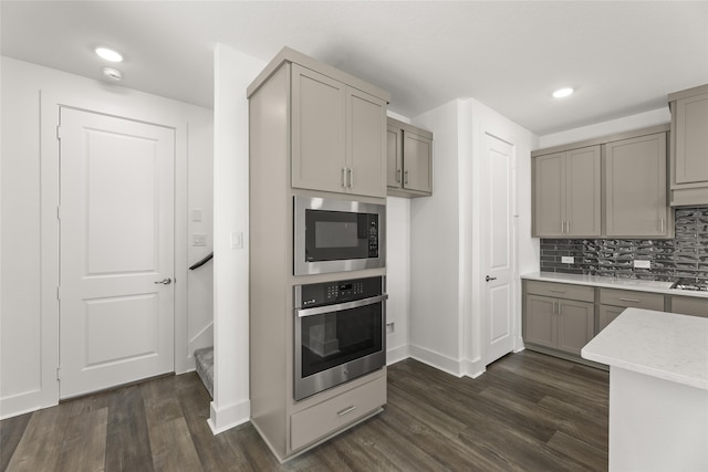 kitchen with gray cabinets, built in microwave, stainless steel oven, and dark wood-type flooring