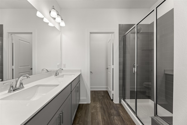 bathroom with a shower with door, vanity, wood-type flooring, and toilet