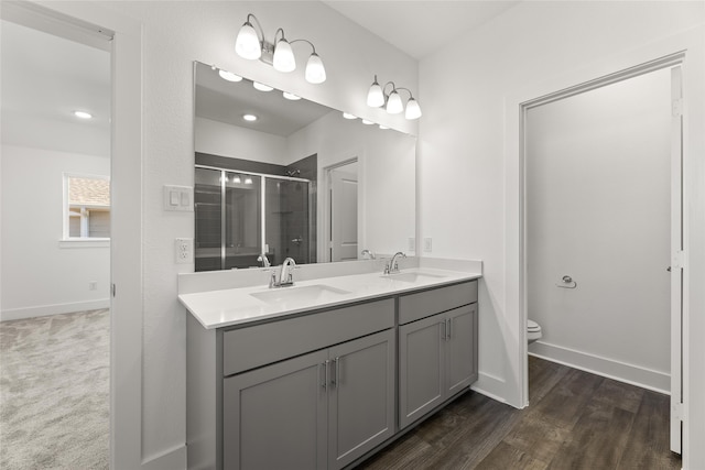 bathroom with hardwood / wood-style floors, vanity, a shower with shower door, and toilet