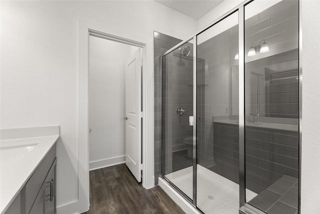 bathroom featuring hardwood / wood-style floors, vanity, toilet, and a shower with door