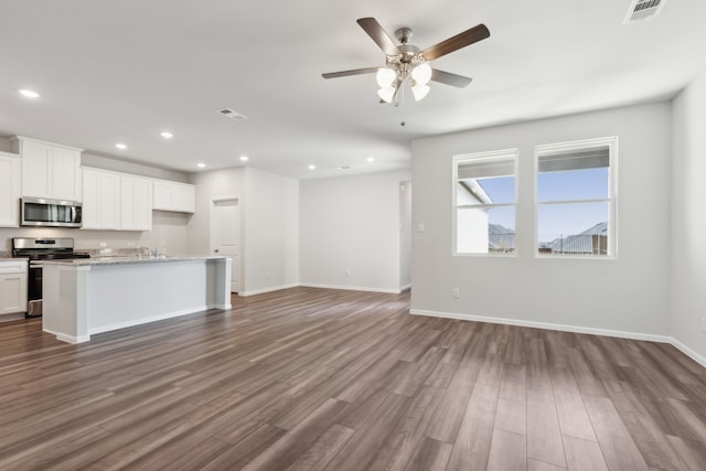 kitchen featuring an island with sink, white cabinetry, decorative backsplash, light hardwood / wood-style flooring, and ceiling fan