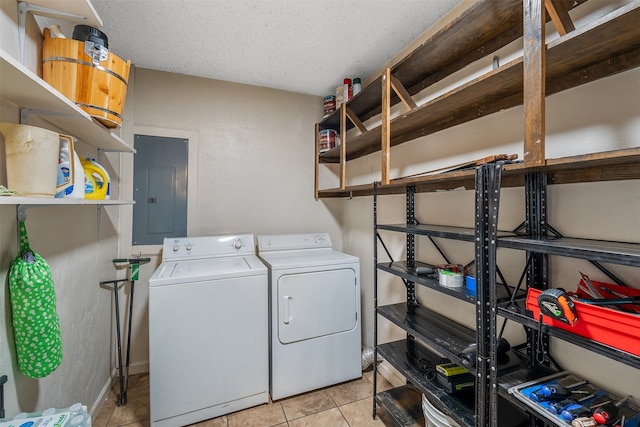 laundry area with a textured ceiling, washing machine and dryer, electric panel, and light tile patterned floors