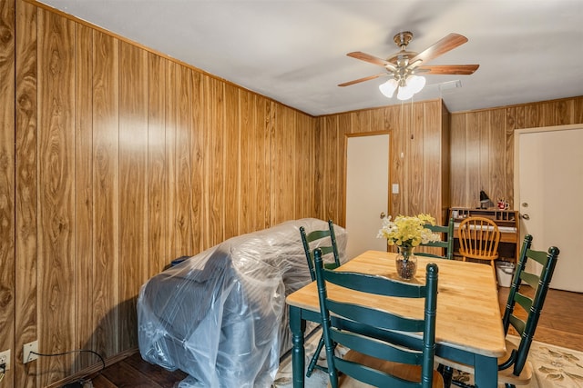 dining area featuring wooden walls and ceiling fan