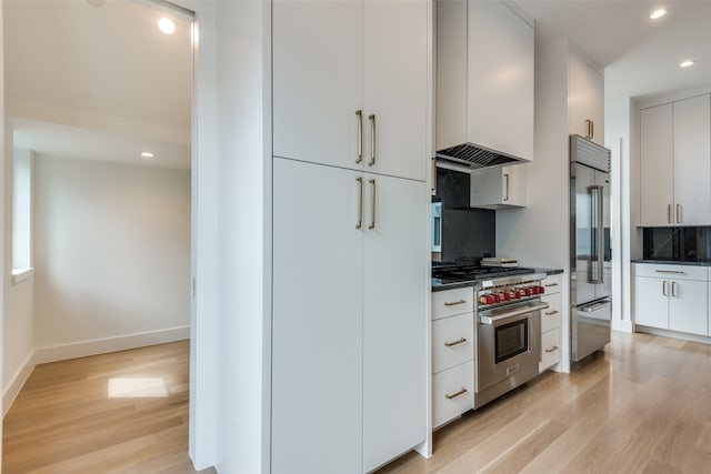 kitchen featuring white cabinets, custom exhaust hood, high end appliances, tasteful backsplash, and light hardwood / wood-style floors