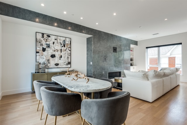 dining space with light hardwood / wood-style flooring and a premium fireplace