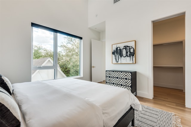 bedroom with a spacious closet, light hardwood / wood-style flooring, and a closet