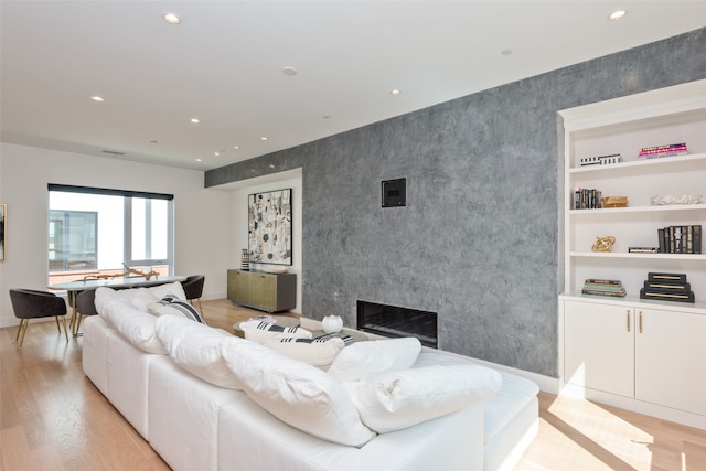 living room with built in shelves and light wood-type flooring