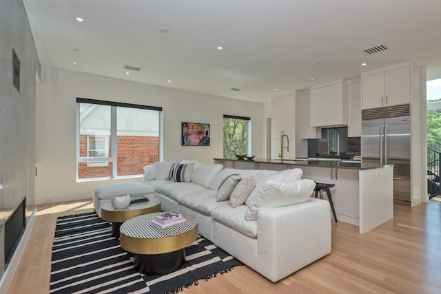 living room featuring light wood-type flooring, sink, and a wealth of natural light