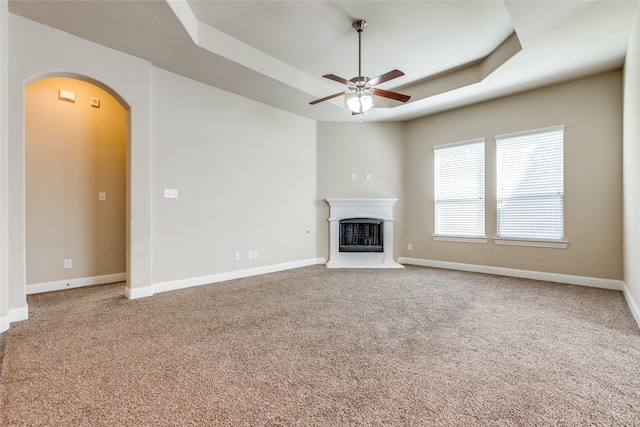 unfurnished living room featuring carpet floors, a raised ceiling, and ceiling fan