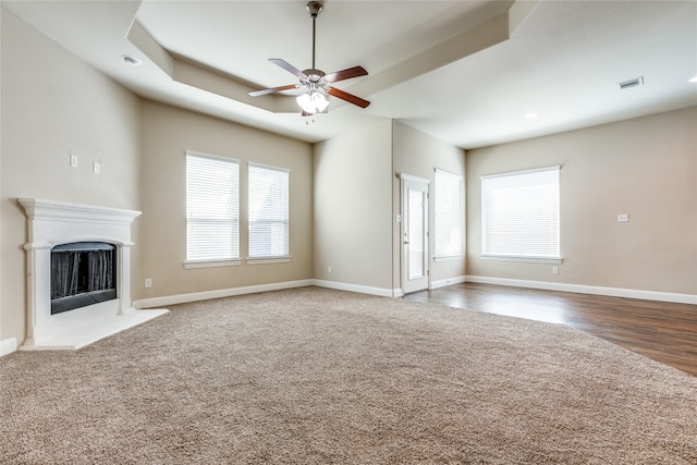 unfurnished living room featuring ceiling fan, plenty of natural light, and dark wood-type flooring