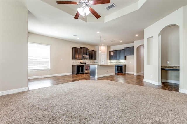 kitchen featuring ceiling fan, pendant lighting, an island with sink, stainless steel appliances, and dark hardwood / wood-style flooring