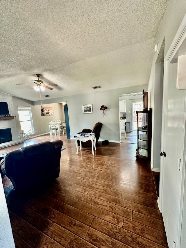 living room with ceiling fan, dark hardwood / wood-style floors, and a textured ceiling